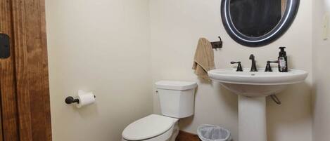 Une petite salle de bain avec des toilettes, un lavabo et un miroir.