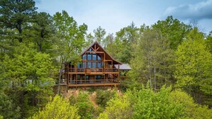 Una cabaña de madera con varios balcones, rodeada de un bosque denso.