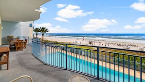 A balcony with a pool, overlooking a beach with people and a flag. - Sterling Breeze 203 (Panama City Beach)