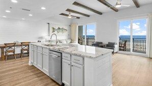 A modern kitchen with white cabinetry, a marble countertop, and a large island. - Sterling Breeze 203 - 1977174 (Panama City Beach)