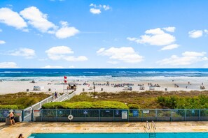 Una platja amb piscina, torre de socorristes i una bandera.