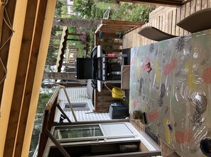 Enjoy al fresco dining and relaxation in this outdoor living space featuring a barbecue grill, seating area, and glass-enclosed view.