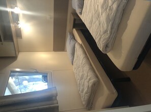 Two beds with white bedding are positioned in this compact room, each supported by dark-colored frames.
