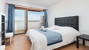 Un dormitorio con una cama, una mesita de noche, una silla, un ventilador y vistas al exterior.