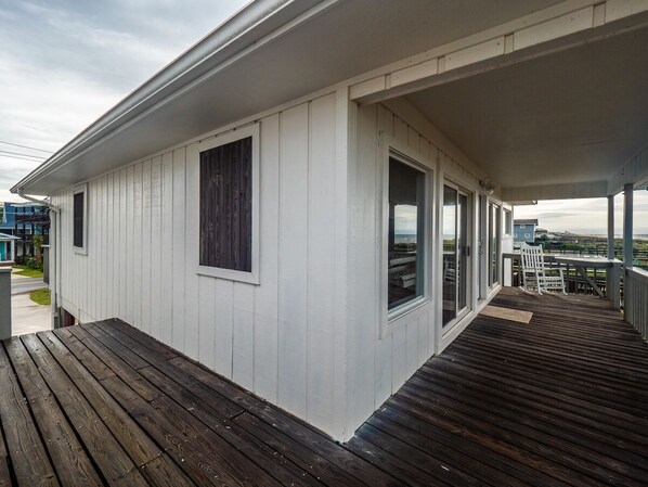 A white building with a wooden deck and large windows.