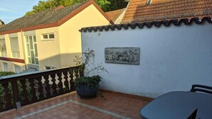 A terrace with a tiled floor, a potted plant, a table, and chairs. - Large apartment / TLA with 3 room-kitchen-bathroom, terrace and balcony (120m²) (Landstuhl)