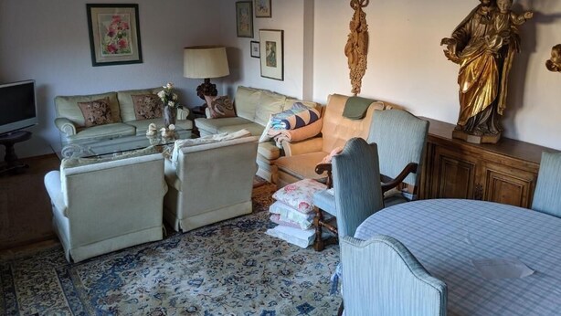 A living room with a sofa, armchairs, a coffee table, and a bed. There are wall decorations including a framed picture and a statue. - Large apartment / TLA with 3 room-kitchen-bathroom, terrace and balcony (120m²) (Landstuhl)