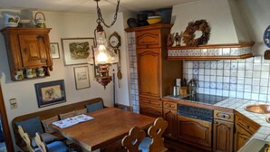 A traditional kitchen with wooden cabinets, a tiled backsplash, and a dining area with a wooden table and chairs. - Large apartment / TLA with 3 room-kitchen-bathroom, terrace and balcony (120m²) (Landstuhl)