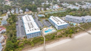 Vue aérienne d’un hôtel situé sur la côte, composé de plusieurs bâtiments, d’un parking et d’une zone de plage.