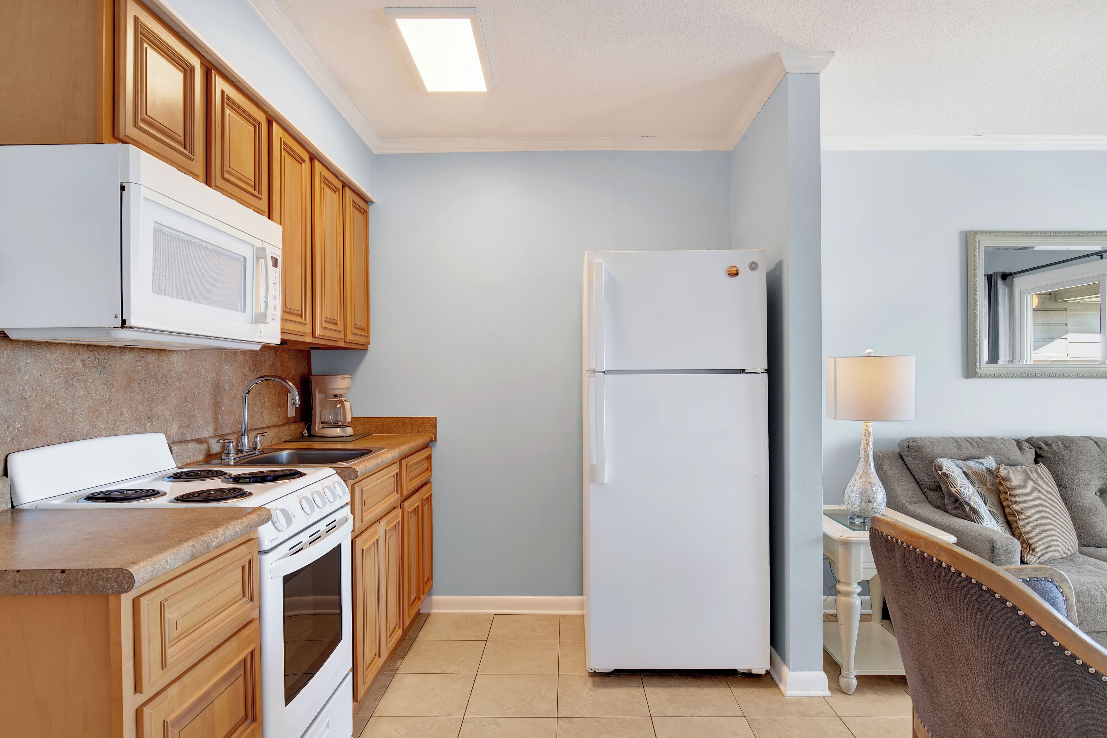 A kitchen with wooden cabinets, a white refrigerator, a stove, and a sink.