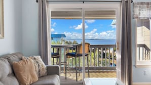 Un balcon avec vue sur la mer, un canapé avec des coussins et une table.