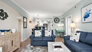 A living room with a sofa, coffee table, and a dining area with chairs and a table.