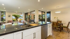 A modern kitchen with a large island, white cabinets, and a dining area with wooden chairs and a table.