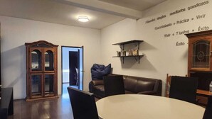 Un comedor con una mesa redonda, sillas, un aparador de madera y una pared con texto motivacional.