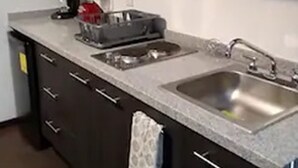 Una cocina con armarios oscuros, encimera de granito, cafetera y un lavabo.