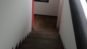 Eine Treppe mit roter Handlauf, schwarzer Wand und einem Fenster oben.