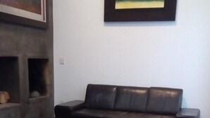 Ein Wohnzimmer mit einem dunkelbraunen Ledersofa, einem Kamin und einem gerahmten Gemälde an der Wand.