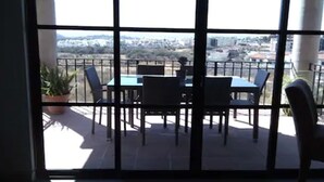 Un balcón con una mesa y sillas, una planta en maceta y vistas de la ciudad.