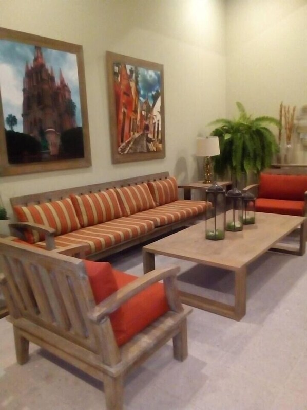 Un salon avec un canapé à rayures, des fauteuils en bois, une table basse et deux tableaux accrochés au mur.