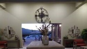 Una habitación amplia con una mesa grande en el centro, un jarrón con flores y un cuadro abstracto de gran tamaño en la pared.