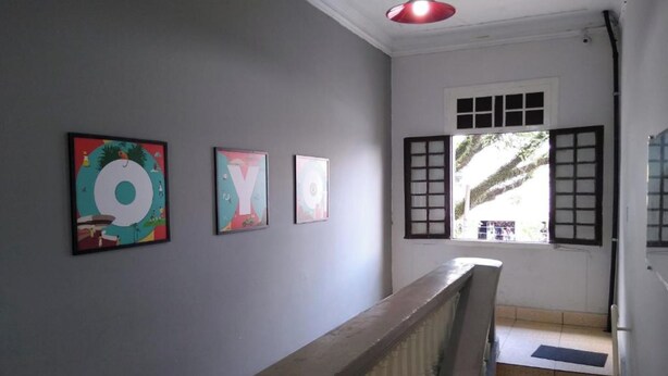 A staircase with a handrail, a window with shutters, and three framed artworks on the wall. - OYO Hotel Brás (São Paulo)