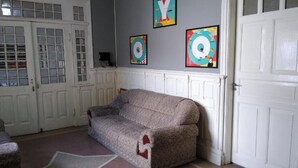 A room with a beige sofa, a white door, and three colorful wall art pieces. - OYO Hotel Brás (São Paulo)