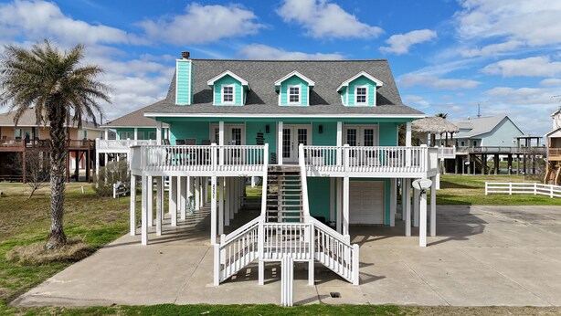A two-story house with a balcony and a staircase leading to the upper level. - Beautiful Crystal Beach Get Away - Close to everything. 3 BR - Sleeps 10 (Bolivar Peninsula)
