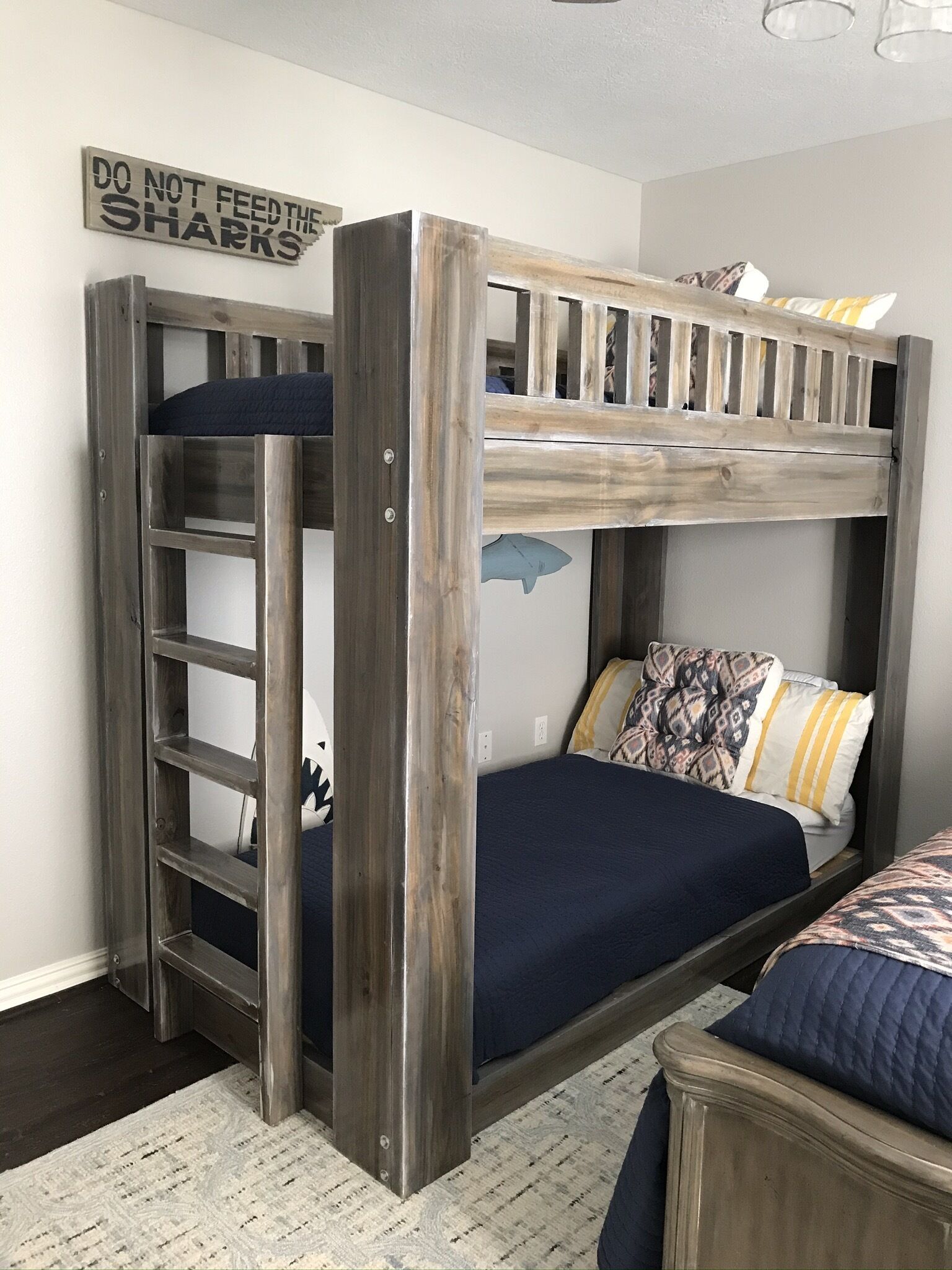 A bunk bed with a ladder, a wall sign, and patterned pillows.