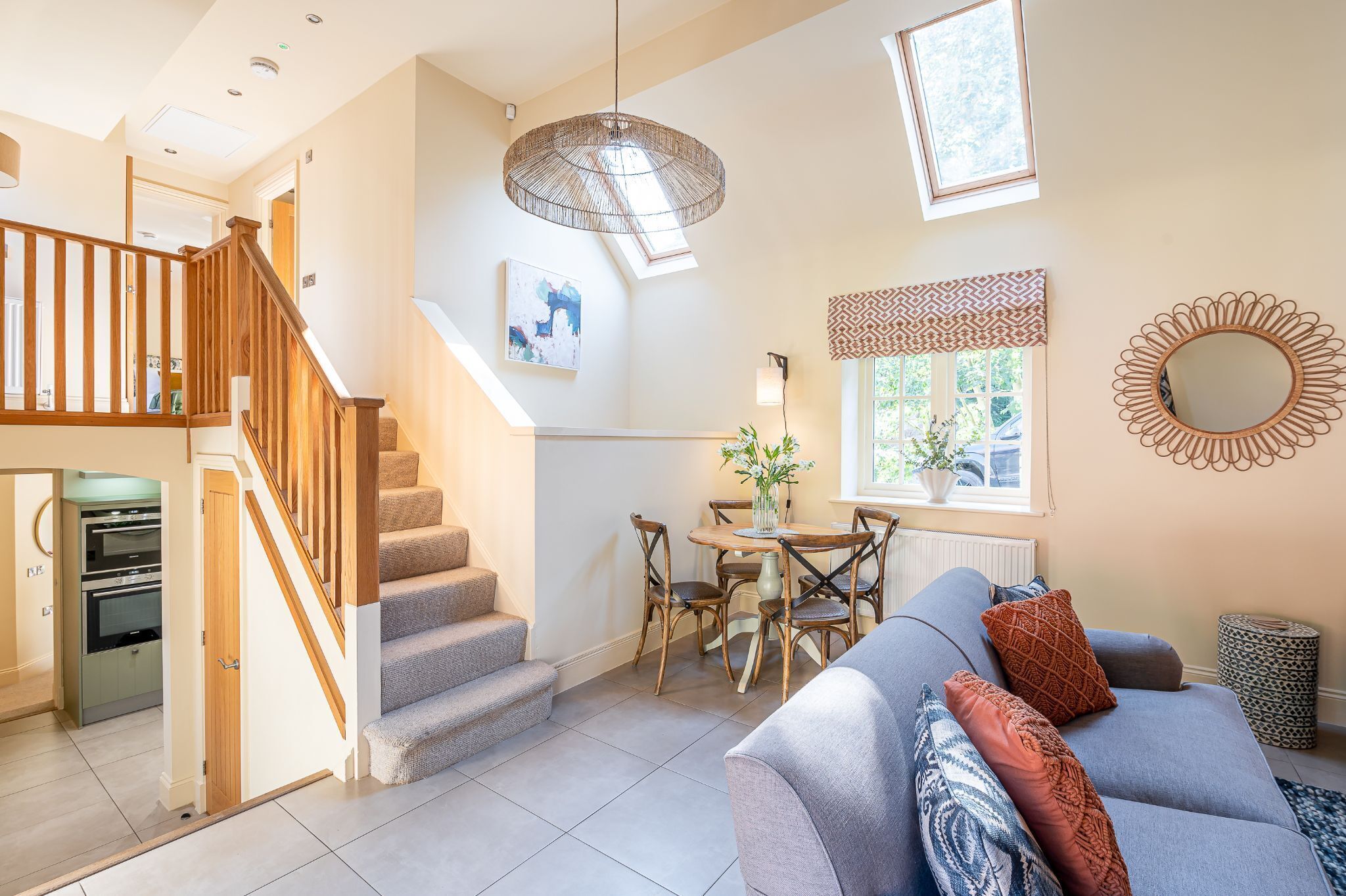 A modern living room with a staircase, a dining area, and a kitchen.