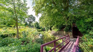 A wooden bridge over a pond surrounded by lush greenery and stone walls. - Sandsend - Rambling Rose -  a family break that sleeps 4 guests  in 2 bedrooms (Whitby)