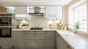 A modern kitchen with a built-in oven, a stove, and a range hood. - Sandsend - Rambling Rose -  a family break that sleeps 4 guests  in 2 bedrooms (Whitby)
