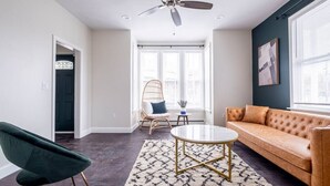 Een moderne woonkamer met een plafondventilator, een bank, een fauteuil en een salontafel.