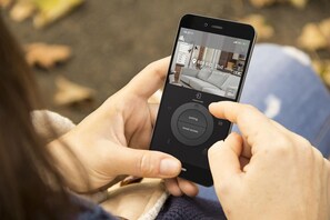 A person using a smartphone to view a hotel room's layout, including a check-in kiosk, parking, and street access. - Jurny - Vanderbilt West End Luxury Flats (Nashville)