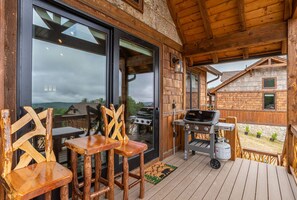 An outdoor deck with wooden chairs, a grill, and a view of a mountain.