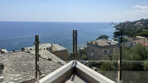 A coastal view from a balcony with stone roofing, overlooking the sea and a town with historic buildings. - Maison au Centre de Pietranera. Premier Étage (San-Martino-di-Lota)