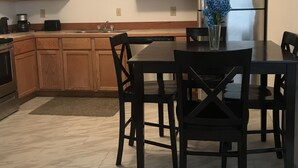 A modern kitchen with wooden cabinets, a stainless steel refrigerator, and a dining table with chairs. - PERFECT for LARGE Groups or FAMILY Reunions (Duchesne)