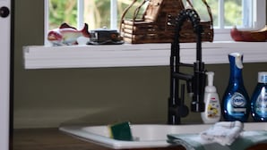 A kitchen with a window, a stained glass decoration, a basket, and kitchen items.