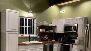 A kitchen with white cabinets, a microwave, a refrigerator, and a wooden countertop.