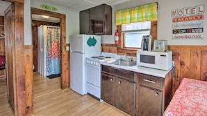 A compact kitchen with wooden cabinets, a refrigerator, a stove, and a microwave. - Charming Laconia Cottage: Walk to Weirs Beach (Laconia)