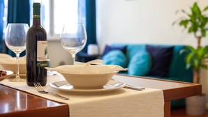 Ein Esstisch mit einer Weinflasche, zwei Weingläsern, einer Schüssel mit Essen und Besteck.