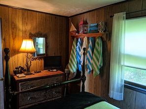 Cozy retreat with a vintage aesthetic, featuring a bed, dresser, TV, and lantern.