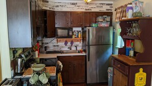A compact kitchen with wooden cabinets, a stainless steel refrigerator, a microwave, and a coffee maker. - Charming 2 Bedroom Lakefront Cottage in the Catskill Mountains (Roscoe)