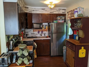 Kitchen features a unique design with a patterned backsplash and a hanging light fixture, complete with a refrigerator, stove, and microwave.
