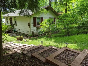 Surrounded by lush greenery, this serene house features a well-maintained garden and a wooden pathway leading to the front door.