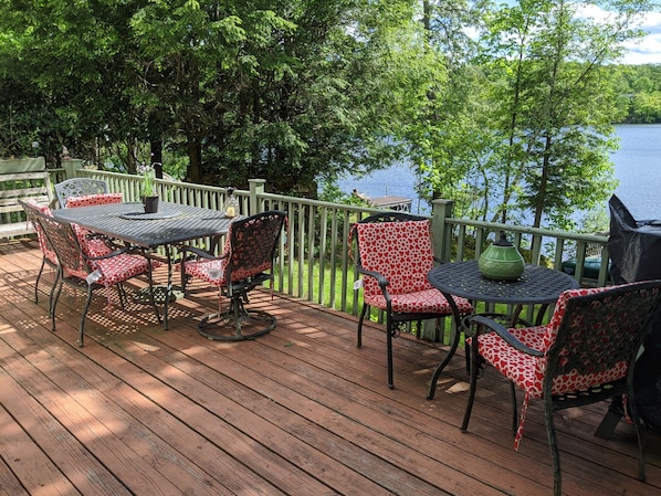 Enjoy a serene view of the water from this deck, surrounded by lush greenery and comfortable seating.