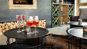 A cozy seating area with a round table, a fireplace, and a wine rack in the background.