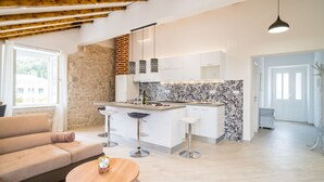 Una cocina moderna con armarios blancos, un salpicadero blanco y negro y una isla central con taburetes.