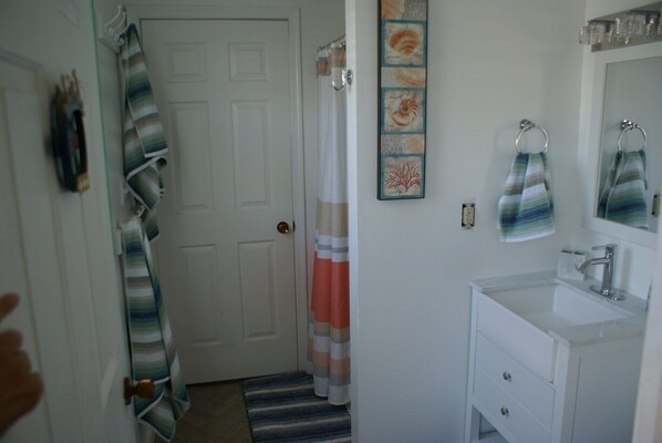 A bathroom with a white sink, a mirror, and striped towels hanging on the wall. - Condo 2 bedroom 2 bath dock (Ocean City)