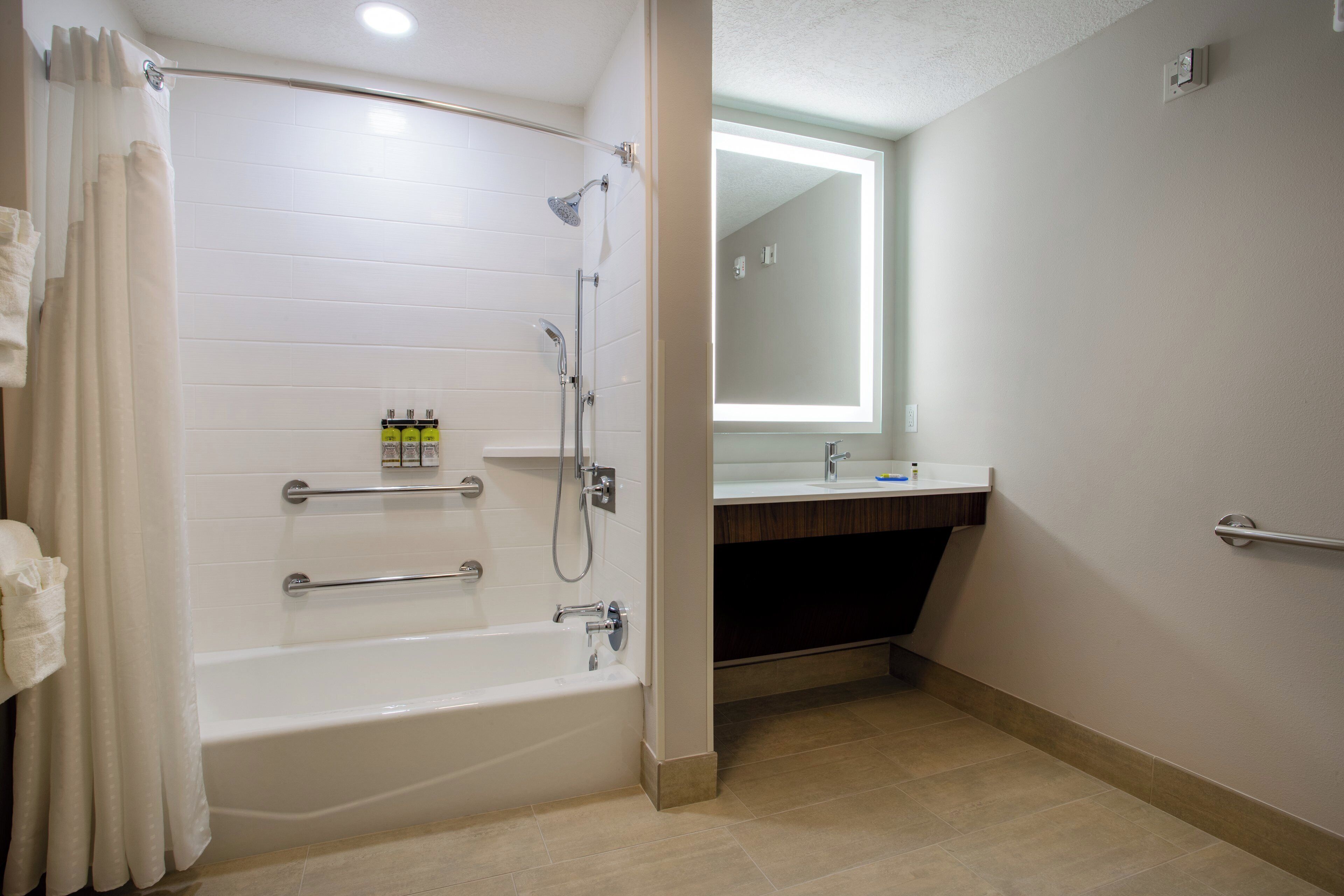 Un baño moderno con bañera, ducha y tocador con espejo.