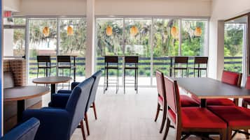 A modern dining area with large windows, wooden tables, and chairs.